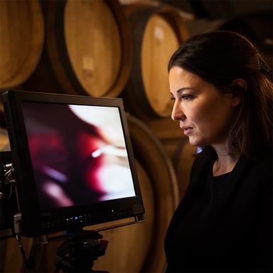Directora de rodaje revisando en un monitor una escena de producto junto a barricas